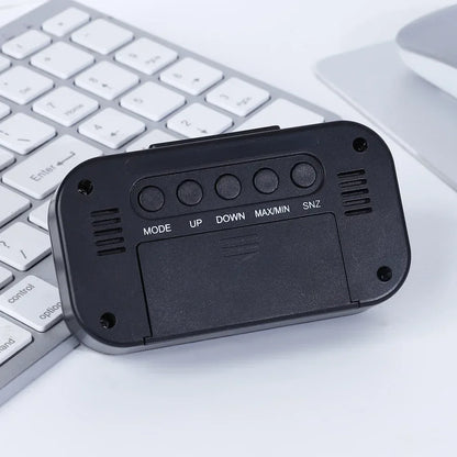 Schwarze Wetterstation-Uhr mit Farbdisplay; Rückseite mit MODE UP DOWN MAX/MIN SNZ-Tasten vor weißer Tastatur.